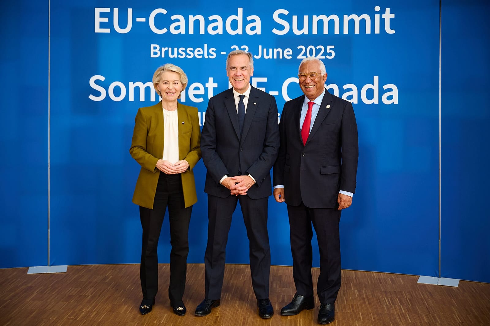 Ursula von der Leyen, Mark Carney and António Costa stand side by side in front of a blue backdrop reading “EU-Canada Summit, Brussels, 23 June 2025”.